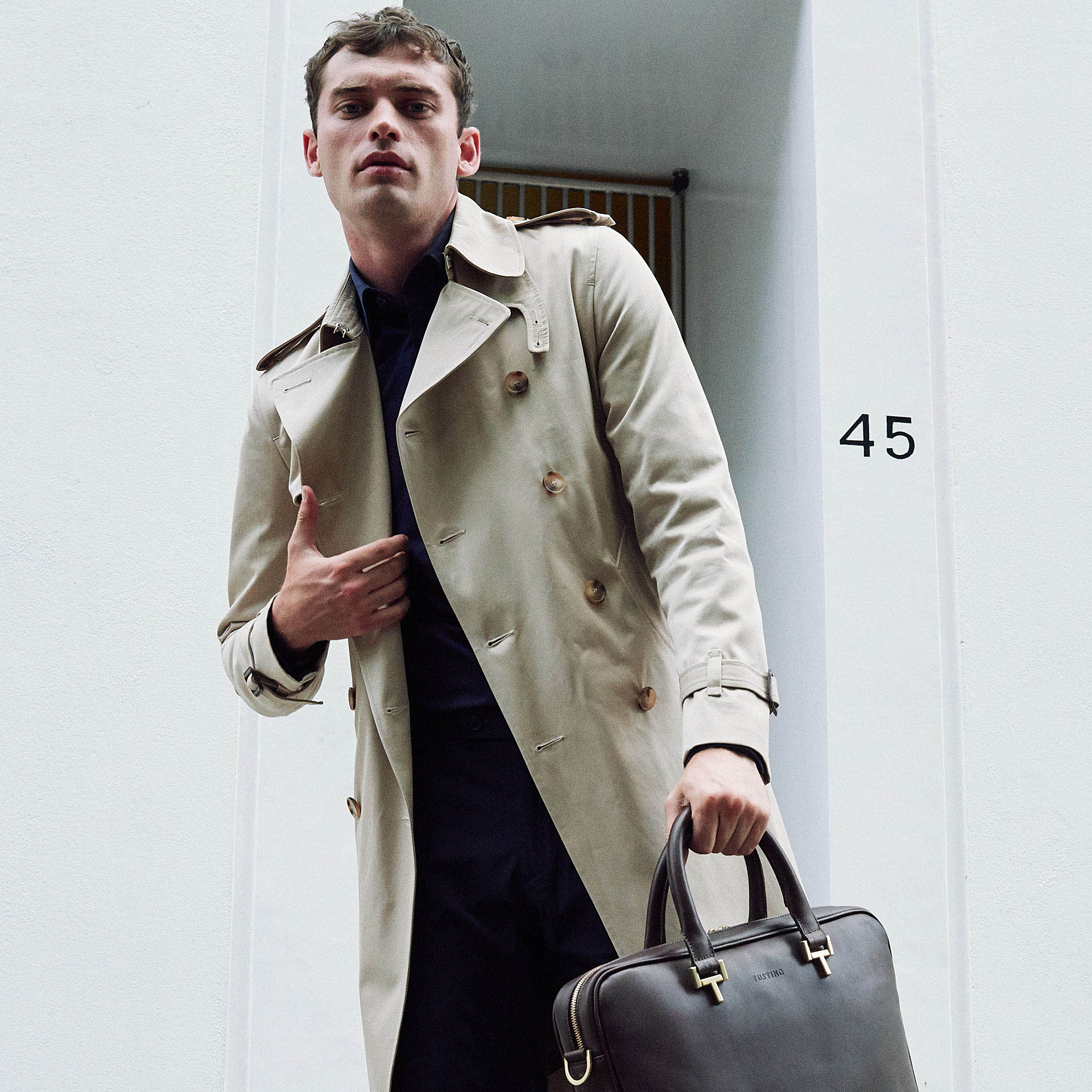 man in raincoat holds black leather briefcase for Tusting