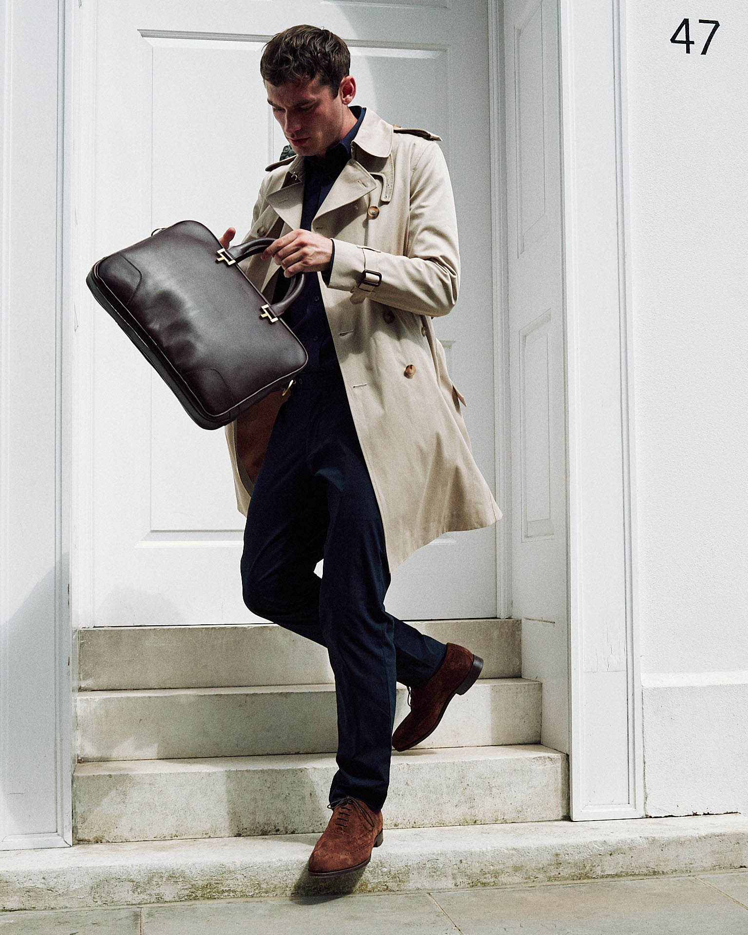 Man in raincoat and holdall  by fashion photographer Tim Cole