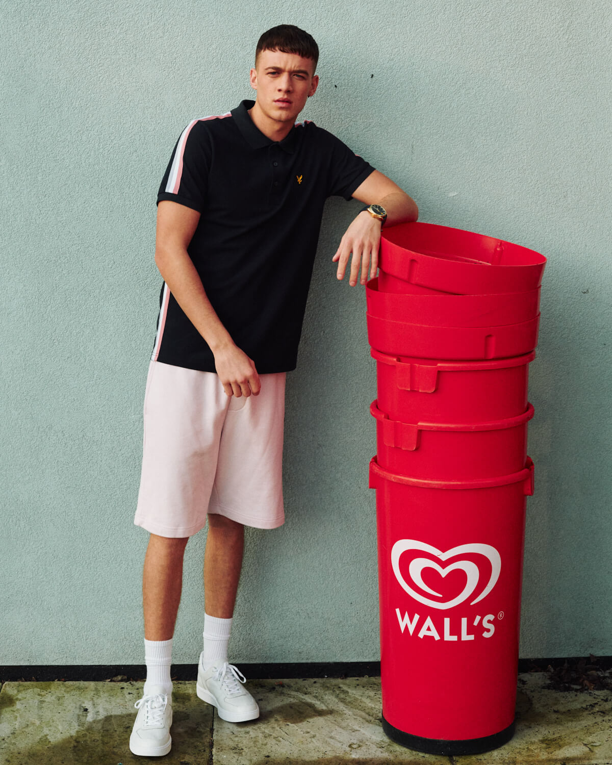 L and S lad  by red bins by lifestyle photographer 