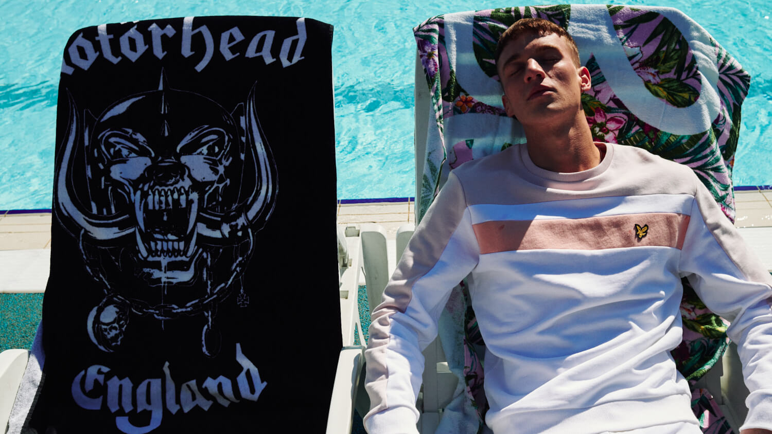 Lad  sits on sunlounger next to motorhead towel