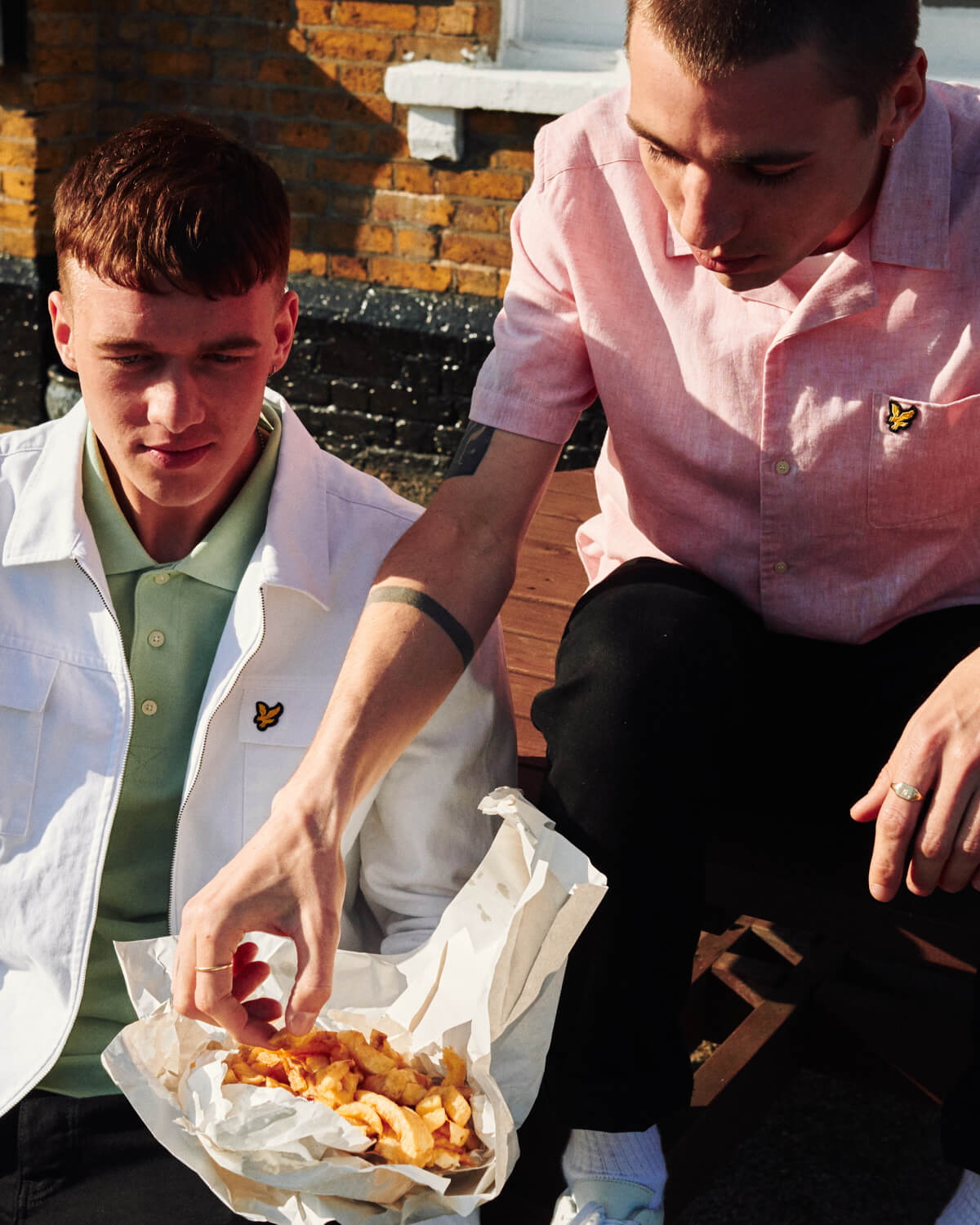 Two lads eating chips by  pub, by lifestyle photographer Tim Cole