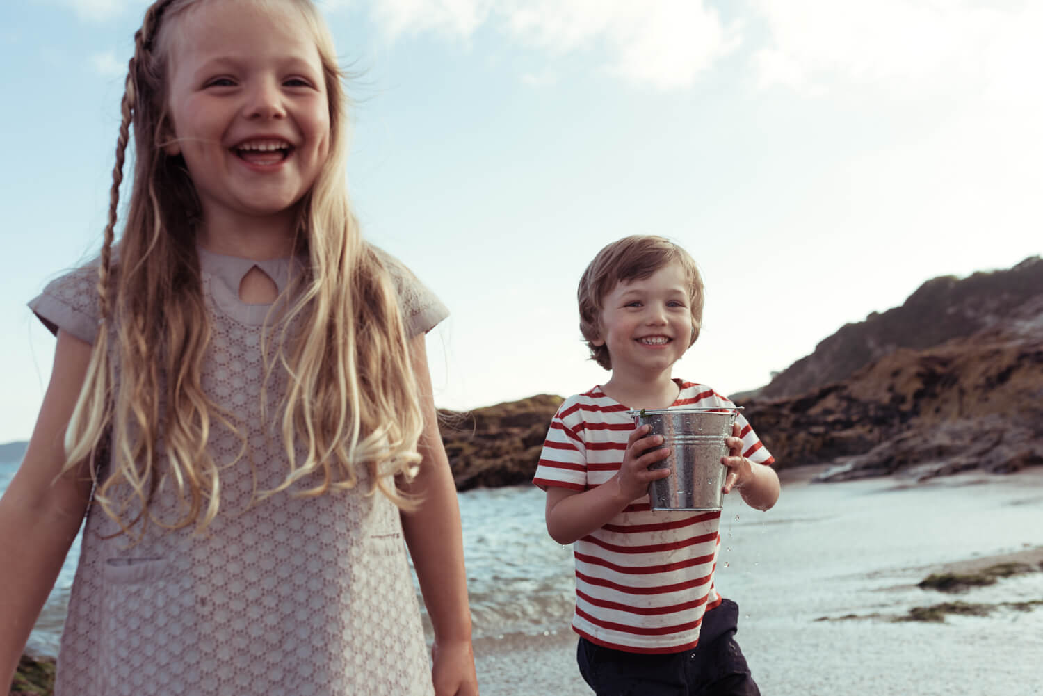 Two kids smiling  by the sea by lifestyle photographer Tim Cole