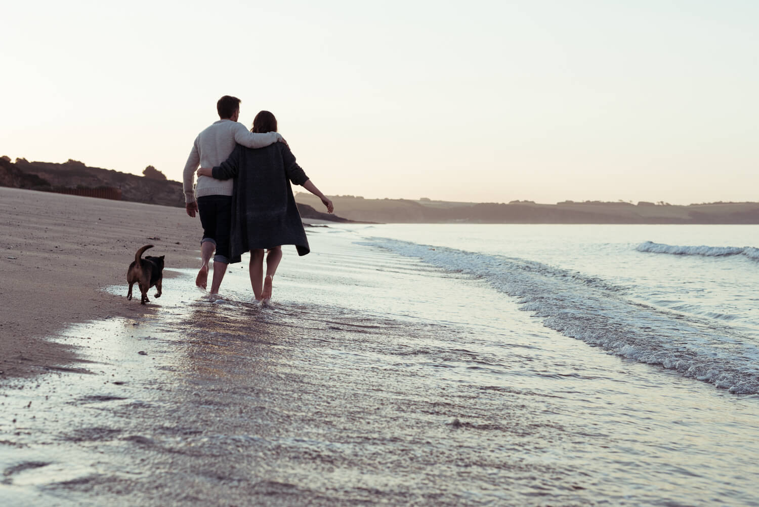 Couple/dog walk the beach  by lifestyle photographer Tim Cole