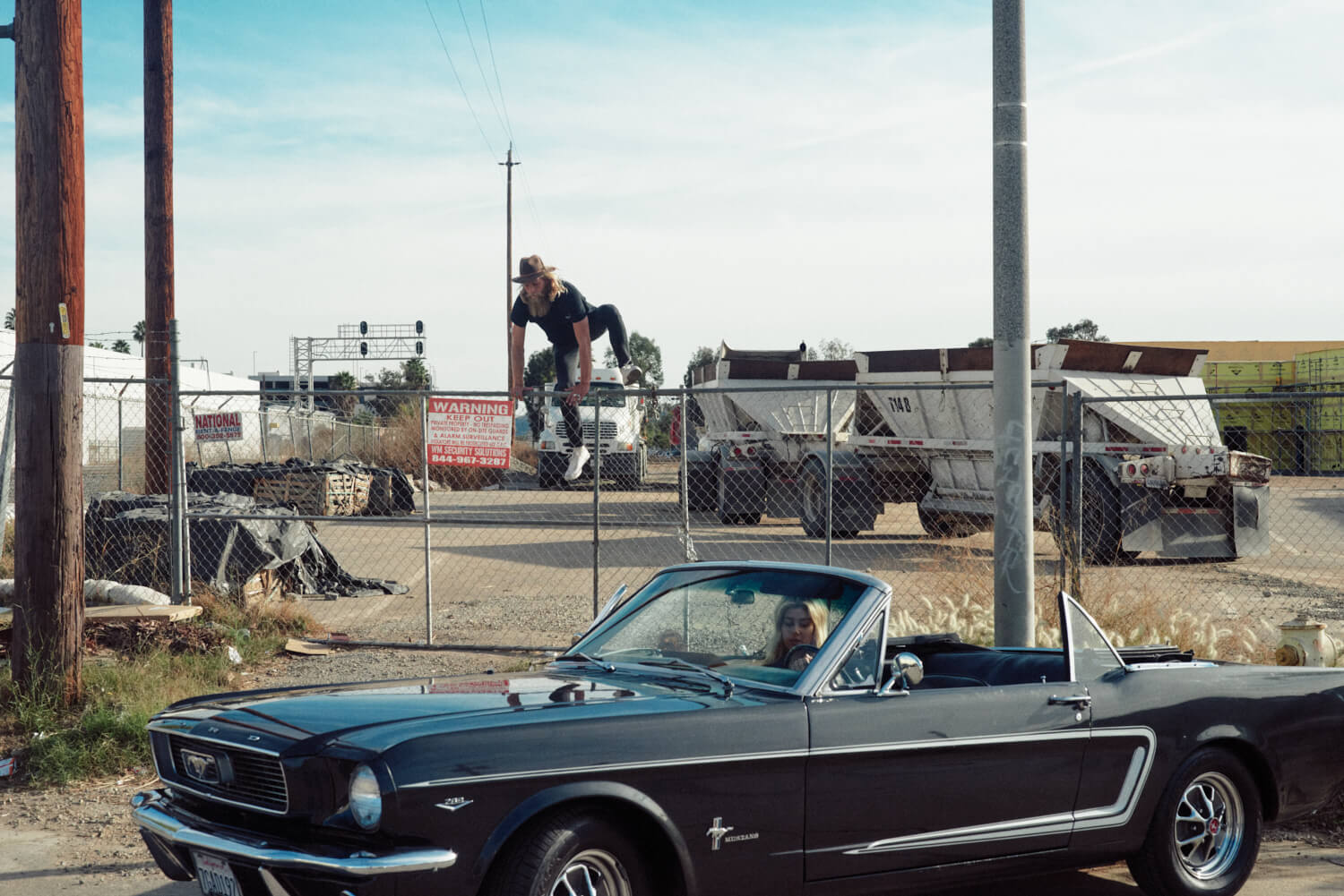 hipster jumps over wire by convertible Ford black mustang 