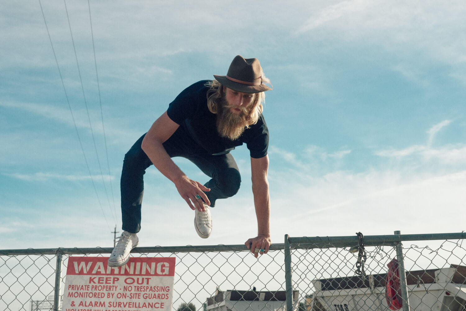 bearded hipster jumps wire by lifestyle photographer Tim Cole