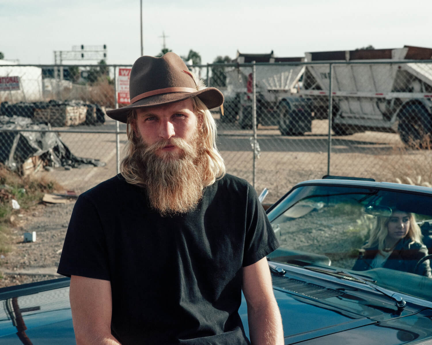 hipster sits on hood by lifestyle photographer Tim Cole