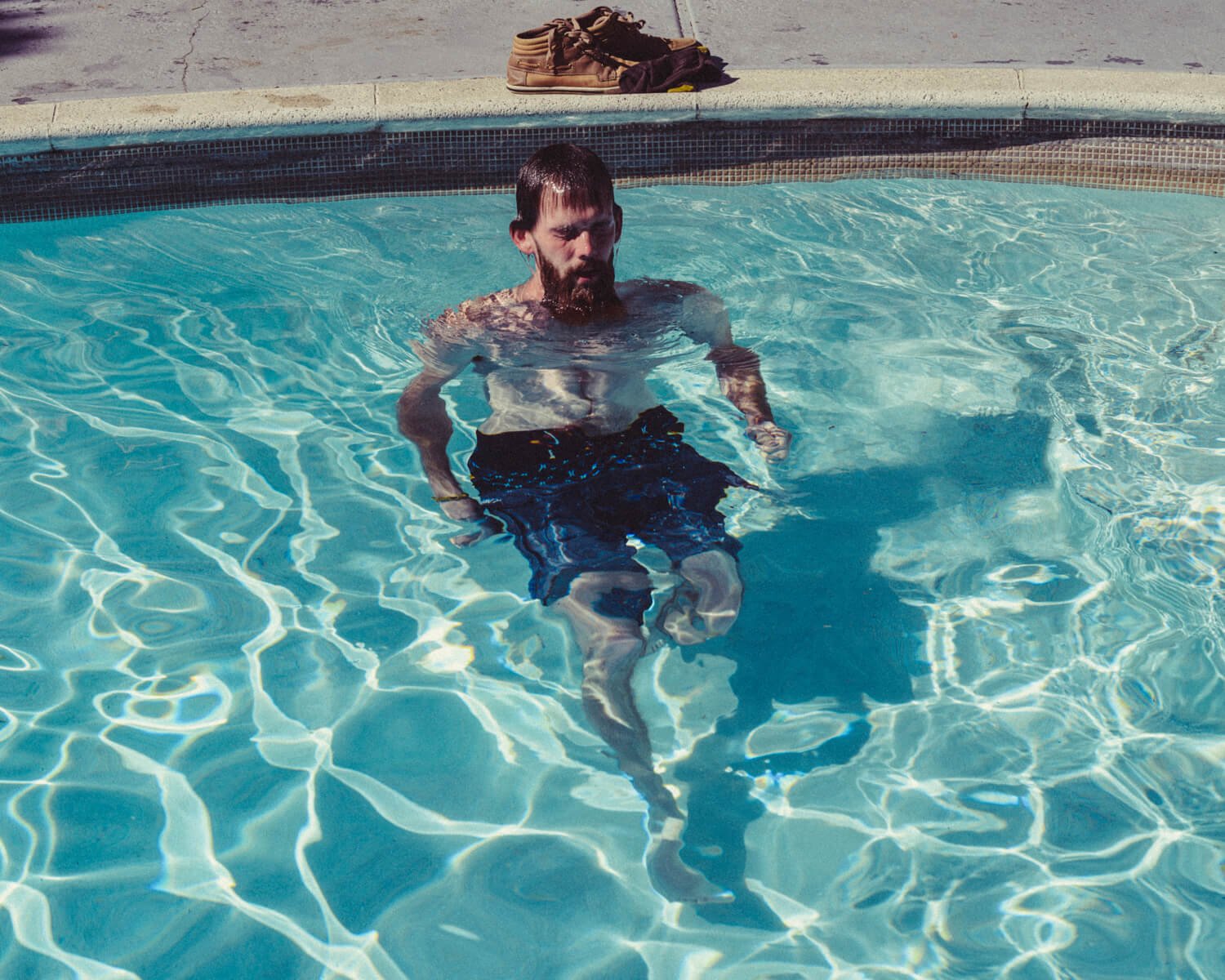 Hipster surfaces in pool by lifestyle photographer Tim Cole