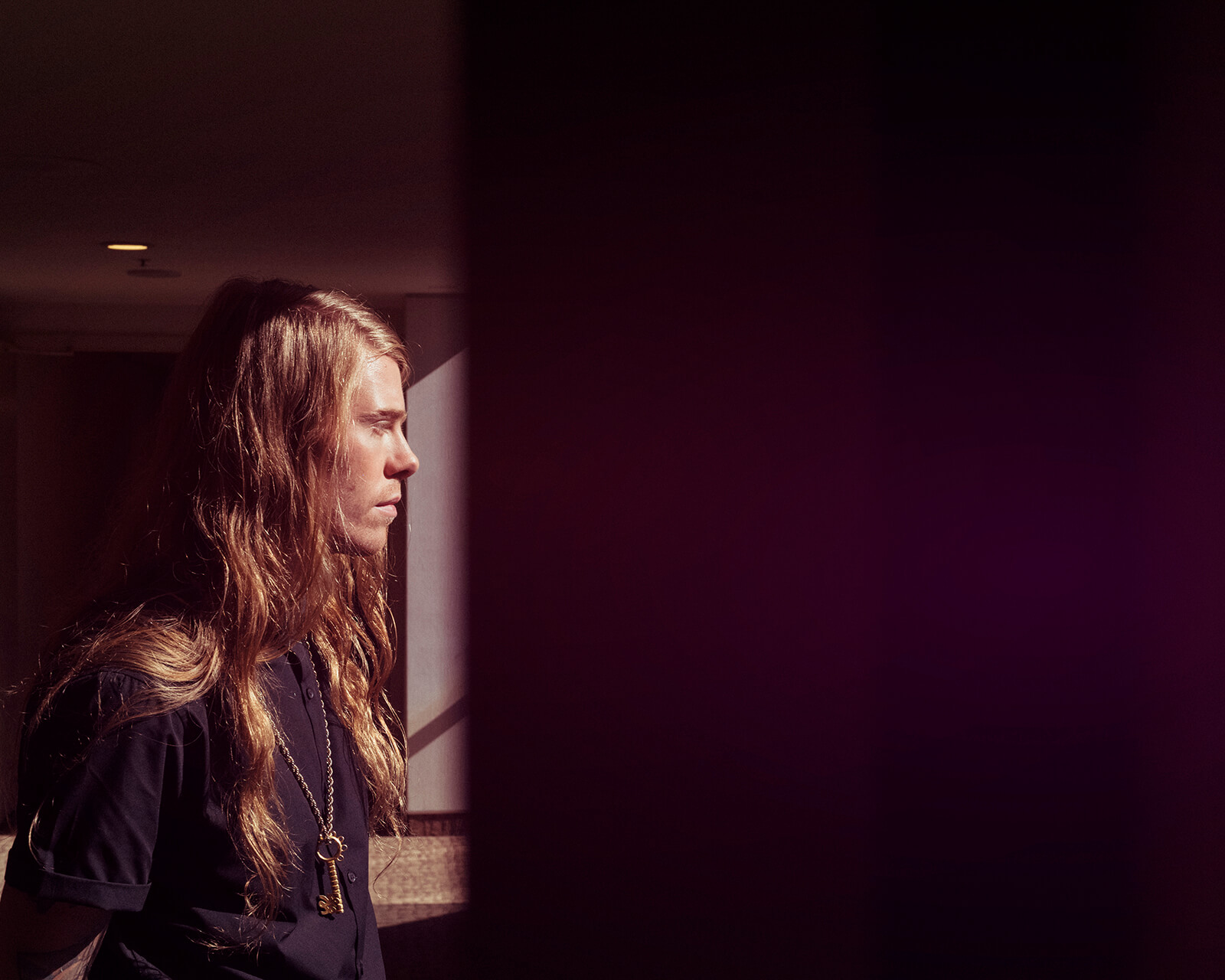 Guy looks out of hotel  window by lifestyle photographer Tim Cole